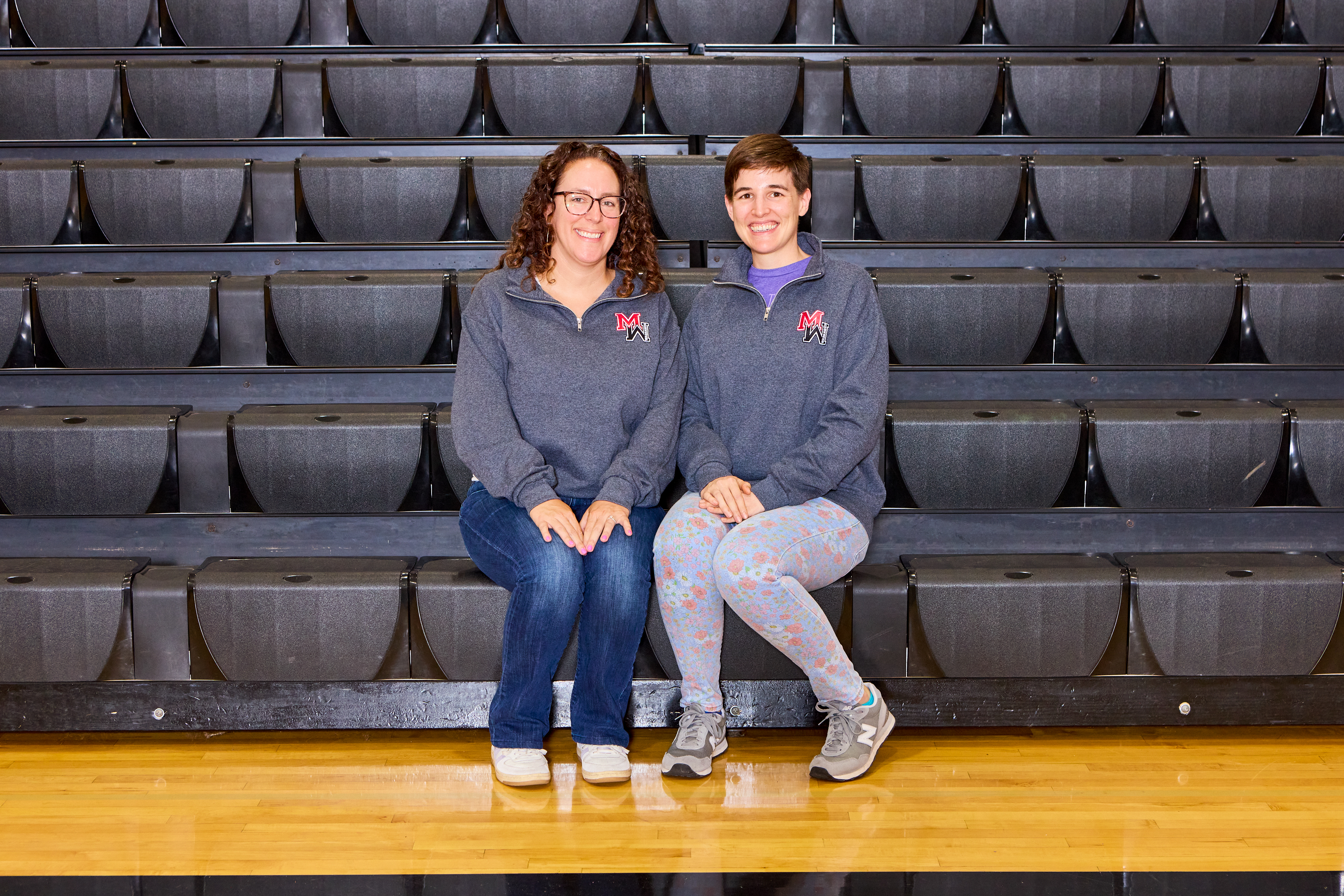 Ms. Liebman and  Ms.McKnight sitting in front of bleachers